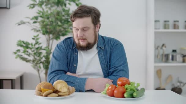 Wahający Się Pulchny Mężczyzna Patrząc Babeczki Warzywa Stole Wybór Żywności — Wideo stockowe