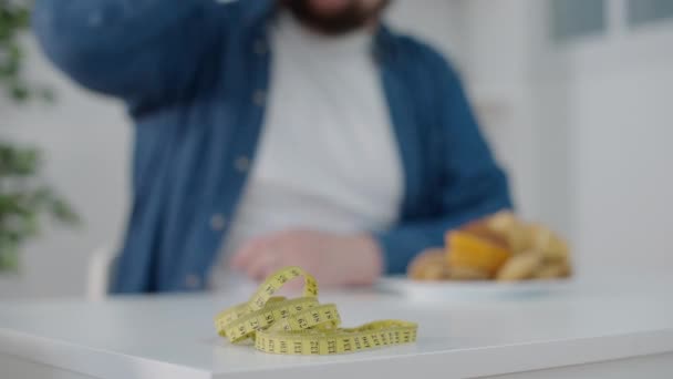 Żółta Taśma Pomiarowa Stole Głodnym Otyłym Mężczyzną Jedzącym Tle — Wideo stockowe