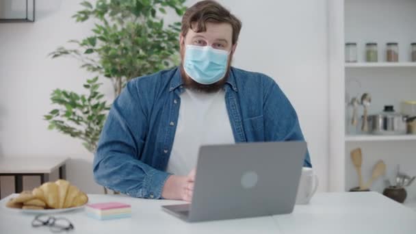 ラップトップの前に座ってマスクの悲しい従業員隔離中の遠隔作業 — ストック動画