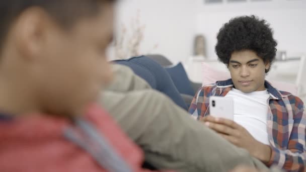 在智能手机上使用移动应用程序的Biracial青少年男孩 在网上订购时面带微笑 — 图库视频影像