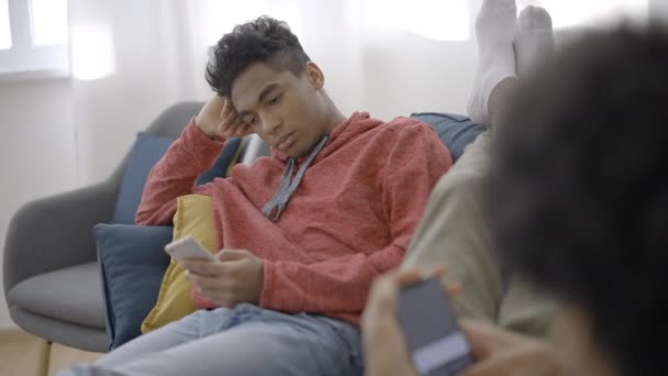 Gelangweilte Teenager Scrollen Smartphones Und Gähnen Auf Der Couch Sitzender — Stockvideo