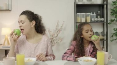 Mutlu anne ve kız sulu elmaları yiyor, sağlıklı beslenme alışkanlıkları var.