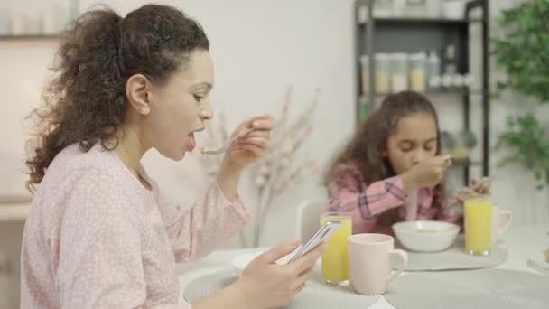 母親と娘は朝食中にスマートフォンに焦点を当て ガジェット中毒 — ストック動画