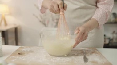 Amatör aşçı. Tabaktaki malzemeleri karıştırıyor. Gülümsüyor, yemek pişiriyor, eğleniyor.