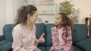 Çok ırklı anne ve kızı koltukta sırlarını paylaşıyor.
