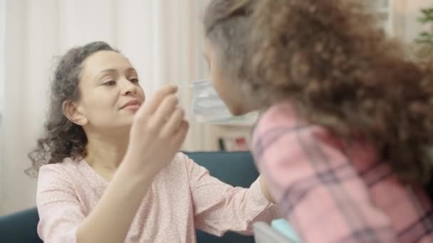 Opiekuńcza Mama Zakładanie Maski Medycznej Małą Córkę Przed Zajęciami Opieka — Wideo stockowe