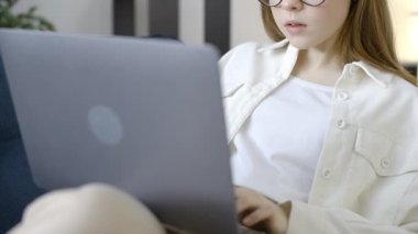 Gözlüklü inek kız öğrenci dizüstü bilgisayarda ödev yapıyor, uzaktan eğitim, uygulama