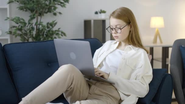Розумна Дівчина Підліток Окулярах Використовуючи Ноутбук Дивані Працює Над Шкільним — стокове відео