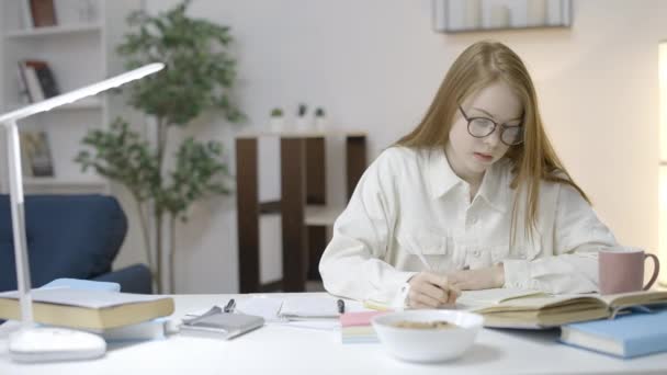 Diligente Chica Adolescente Gafas Leer Libro Escribir Ensayo Casa — Vídeo de stock