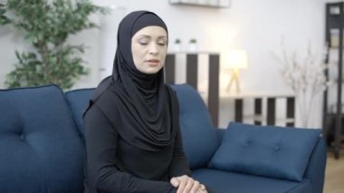 Sinirli müslüman kadın koltukta oturuyor, evde kocasını bekliyor, depresyonda.