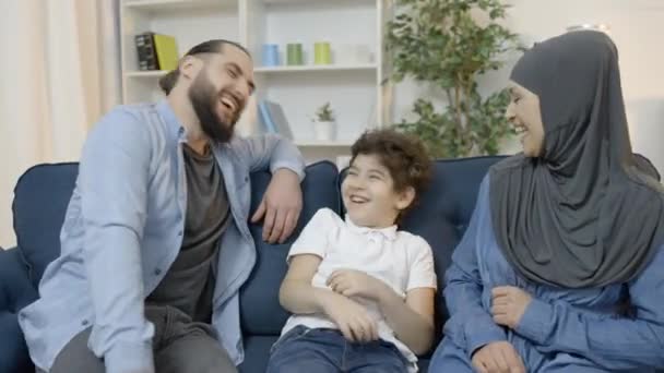 Animados Pais Muçulmanos Filho Rindo Juntos Sentados Sofá Casa Lazer — Vídeo de Stock