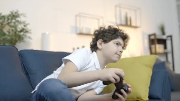 コントローラーでビデオゲームをプレイする不安少年 顔に不快感 — ストック動画
