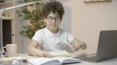 Akıllı okul çocuğu ev ödevi yapıyor, bilgisayar kullanıyor, telefonları görmezden geliyor.