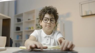 Akıllı okul çocuğu dizüstü bilgisayar klavyesinde ev ödevi yazıyor, bilgisayar okur yazarlığı.