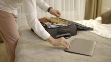 İş seyahatine hazırlanan bir kadın, dizüstü bilgisayarını bavula koyup iş konferansına gidiyor.