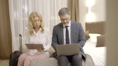 Tabletli kadın ve erkek otel ve iş seyahatlerinde kontrat detaylarını tartışıyorlar.