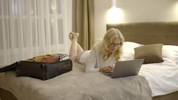 Szczęśliwa Dojrzała Kobieta Pracuje Laptopie Leży Łóżku Komfortowym Pokoju Hotelowym — Wideo stockowe