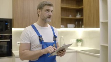 Tamirci tablet üzerinde çalışıyor, ev bakımı uygulaması ve teknoloji kullanıyor.