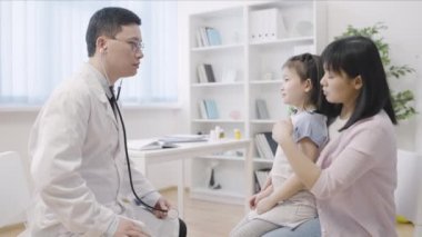 Çocuk doktoru Asyalı kızı muayene ediyor anne ve çocuk tedavi için doktoru ziyaret ediyor