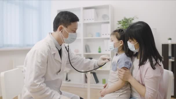Dokter Keluarga Laki Laki Memeriksa Gadis Kecil Asia Dengan Stetoskop — Stok Video