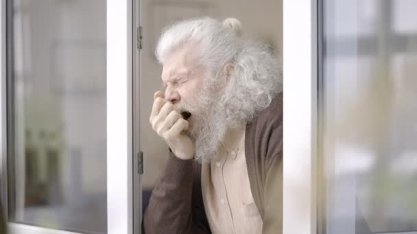 Yaşlı Büyükbaba Esniyor Pencereden Dışarı Bakıyor Emeklilikten Sıkılmış Hissediyor — Stok video