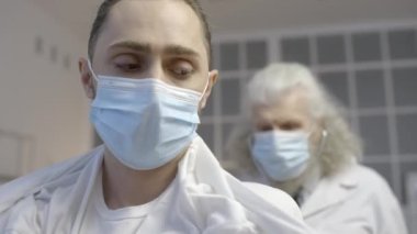 Hastanede akciğer muayenesi sırasında maske takan genç bir adam.