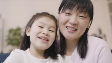 Asyalı kız ve anne konuşuyor ve gülümsüyor, video çağrısı yapıyor, modern teknoloji