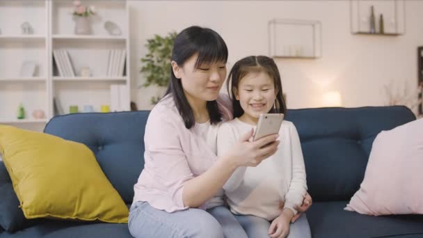 Szczęśliwa Azjatycka Matka Córeczka Pomocą Aplikacji Mobilnej Smartfonie Uśmiechnięta — Wideo stockowe