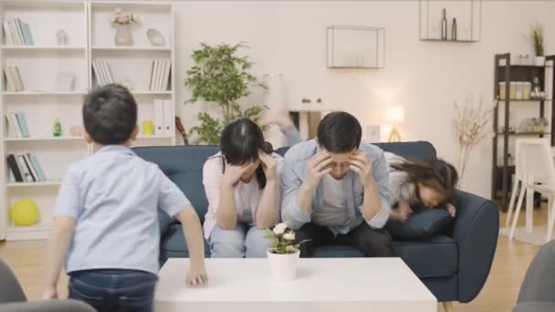 Esausti Genitori Asiatici Seduti Sul Divano Impotenti Bambini Che Giocano — Video Stock