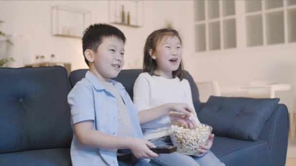 Asiático Pequeño Niño Chica Viendo Comer Palomitas Maíz Sofá Casa — Vídeo de stock