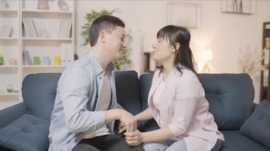 Romantik Asyalı çift kanepede öpüşüyor ve sarılıyor, aşk ilişkisi, mutluluk