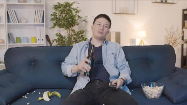 Pigro Asiatico Giovane Uomo Seduto Divano Con Birra Snack Commutazione — Video Stock