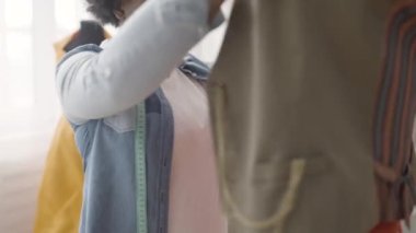 Moda stüdyosunda manken kıyafetlerine bakan serbest çalışan bir terzi.