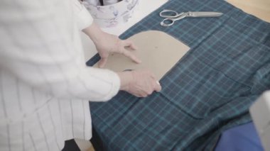 Terzi dikiş deseni kullanıyor, kumaşı işaretliyor, atölyede elbise yapıyor, tasarım yapıyor.