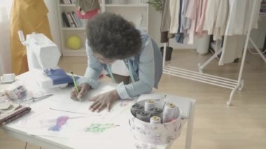 Siyah terzi elbise atölyesinde tasarım çizimi yapıyor, moda trendleri
