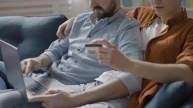 Eşcinsel çift dizüstü bilgisayardaki banka kartından ödeme yapıyor, online alışverişin keyfini çıkarıyorlar.