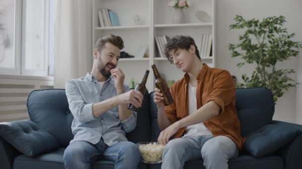 Männliche Freunde Trinken Bier Und Essen Popcorn Auf Der Couch — Stockvideo