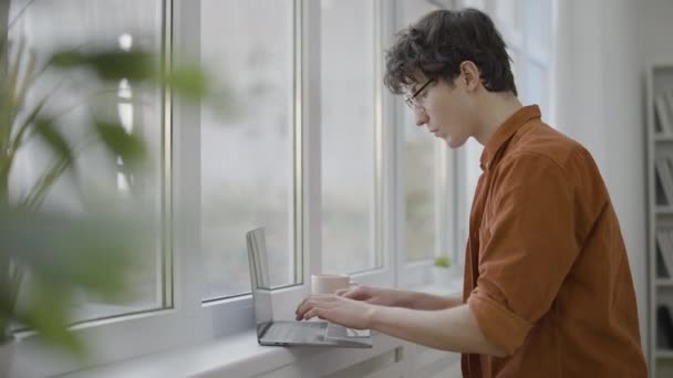 Jovem Ocupado Trabalhando Laptop Perto Janela Freelancer Trabalhando Projeto — Vídeo de Stock