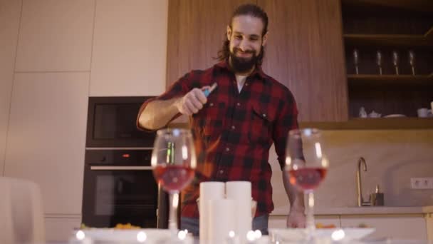 家でロマンチックなディナーを準備トルコ人の男を笑顔 ろうそくに火をつけ — ストック動画