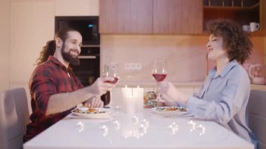 Mutlu genç çift kadeh tokuşturuyor, evde yıldönümünü kutluyorlar, randevudalar.