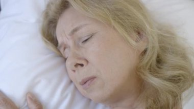 Stresli orta yaşlı kadın yatakta yatıyor, ağlıyor ve gergin bir gerilim hissediyor.