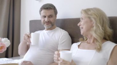 Mutlu bir çift kahve içiyor ve sabahın köründe yatakta sohbet ediyor.