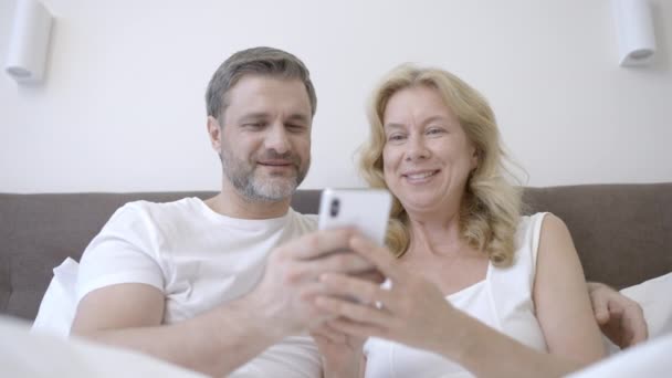 Glückliches Liebespaar Mittleren Alters Scrollt Smartphone Zusammen Und Ruht Sich — Stockvideo
