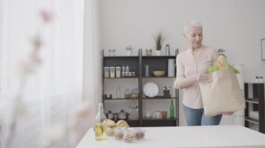 Kese kağıdından meyve ve sebze çıkaran sıska bir kadın, sağlıklı bir hayat.