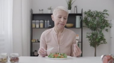 Mutsuz kadın sebze salatası yiyor, diyet yapmaktan ve sağlıklı beslenmekten bıktı.