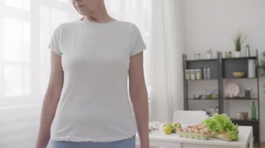 Formda, orta yaşlı bir kadın, kemer, spor ve ağırlık kontrol diyeti ile bel ölçümü yapıyor.