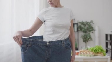 İnce bayan ekstra büyük kot pantolon giyiyor, kilo kaybı diyet sonuçlarından memnun.