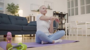 Sağlıklı orta yaşlı kadın kollarını açıyor, lotus pozisyonunda oturuyor, yoga egzersizi yapıyor.