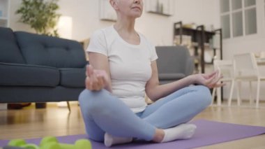 Nilüfer pozisyonunda oturan zayıf kadın, rahatlamak için meditasyon yapıyor, vücut ve zihin dengesi.