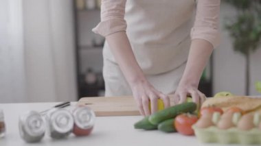 Mutfakta ellerinde meyvelerle dans eden mutlu bayan sağlıklı yemekler pişiriyor, ağır çekimde.